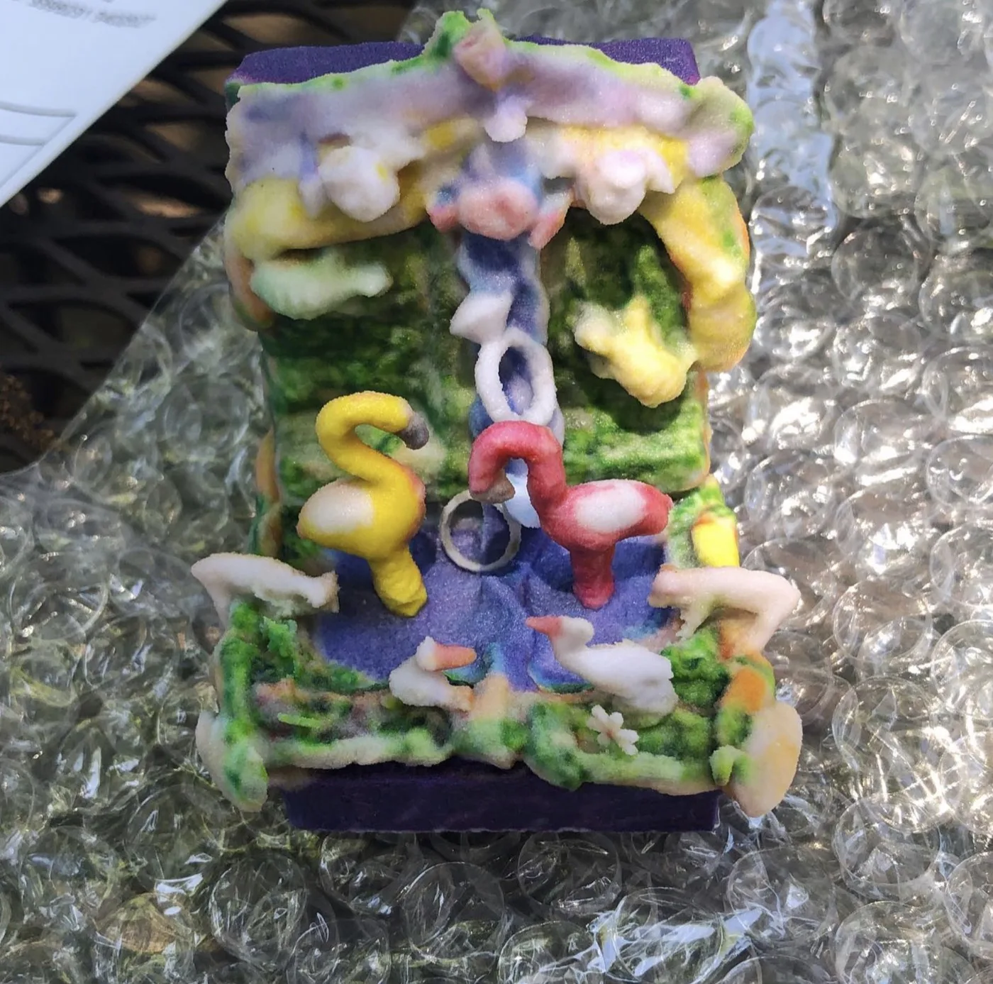 Full-color 3D printed custom flash drive: a grotto-like arch with flamingos, wedding rings, and foliage, photographed on bubble wrap