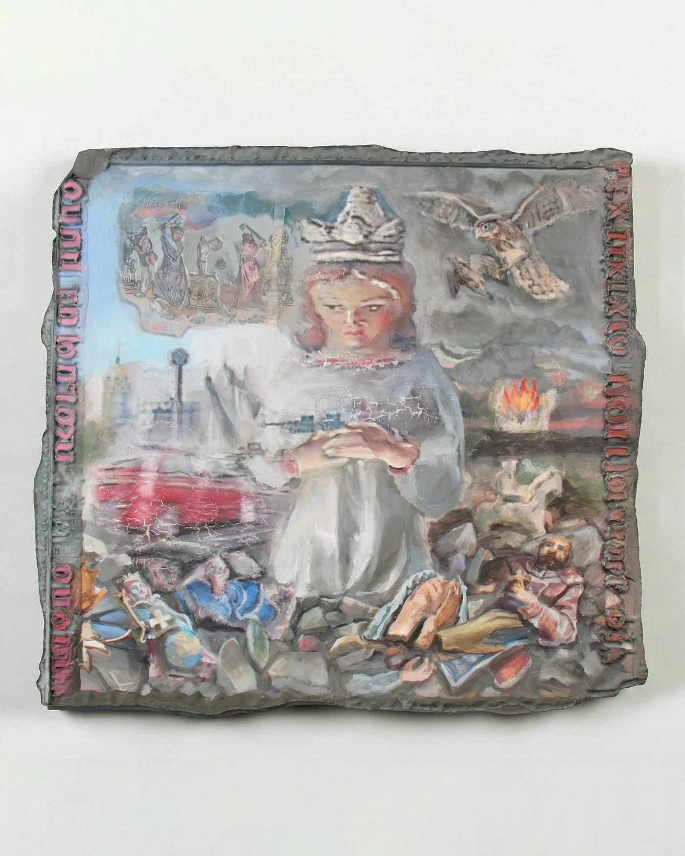 Relief painting on an irregular slate-gray panel: a crowned doll-like figure at center with clasped hands, a falcon flying above, a burning crown, heaps of toy figures and a sleeping man below, and red inscriptions running along the borders